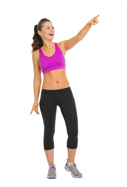 Full length portrait of smiling fitness young woman pointing on — Stock Photo, Image