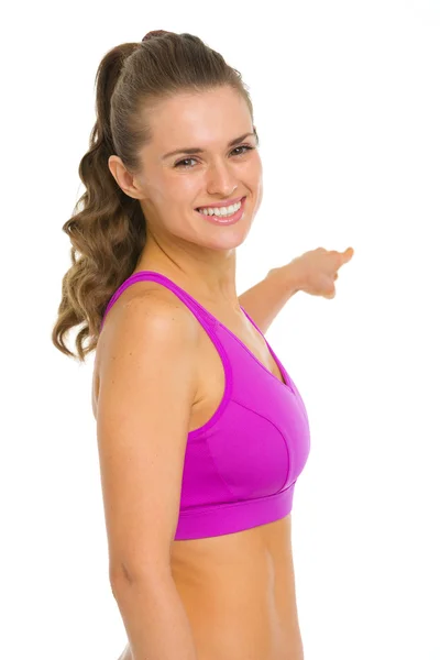 Portrait of smiling fitness young woman pointing back on copy sp — Stock Photo, Image