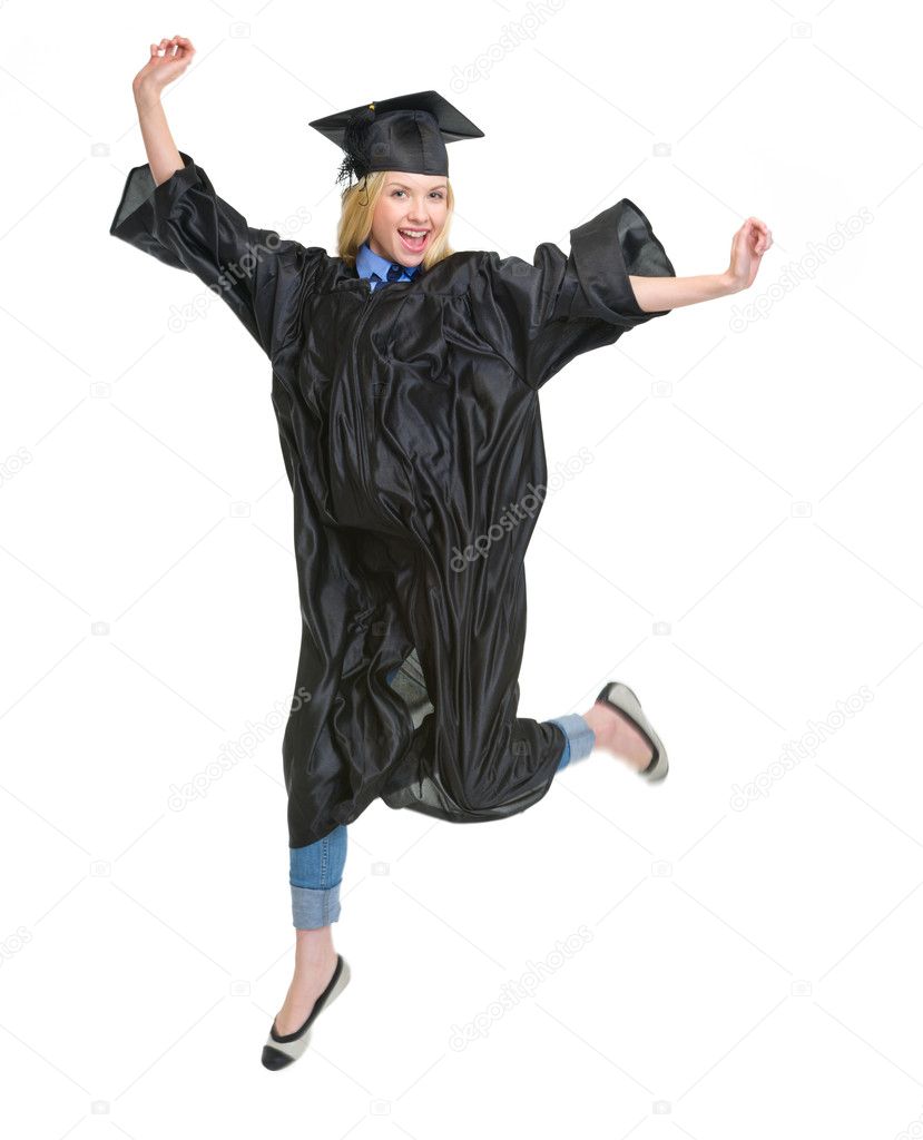 Full length portrait of young woman in graduation gown jumping