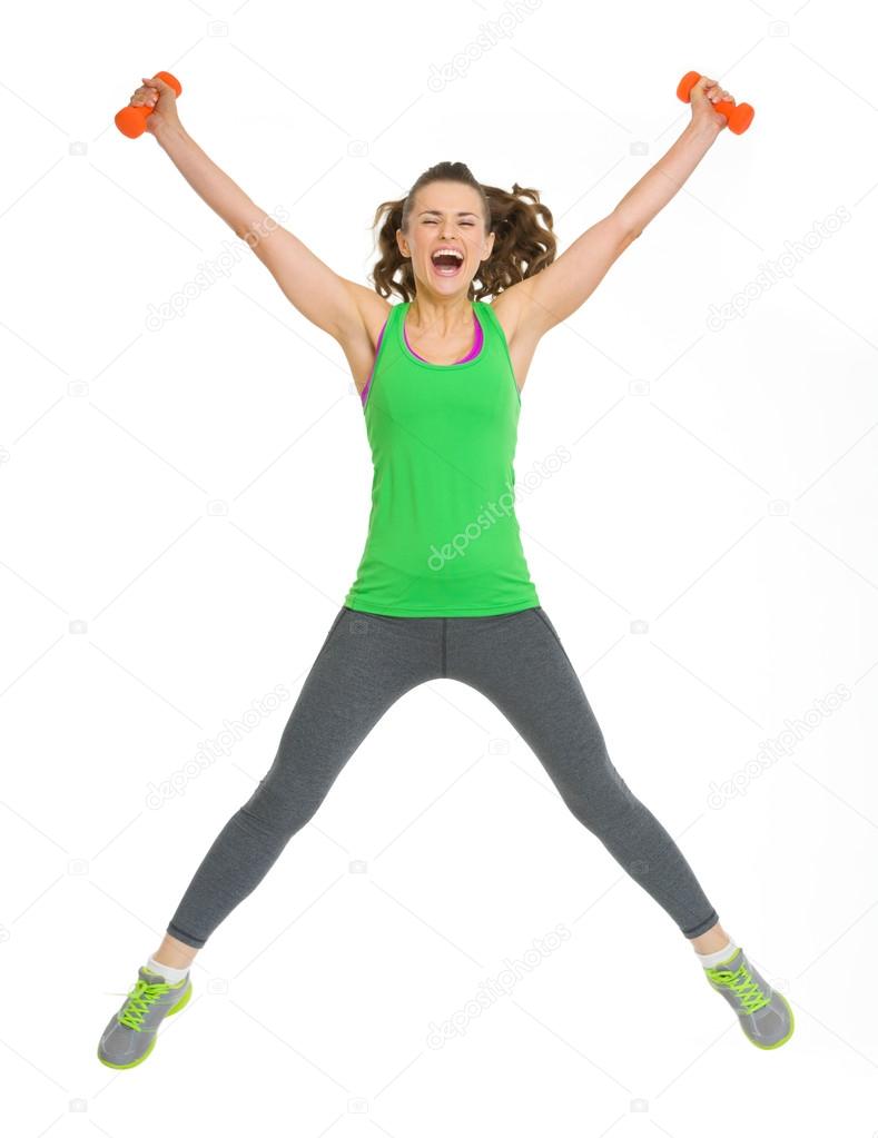 Happy healthy young woman with dumbbells jumping