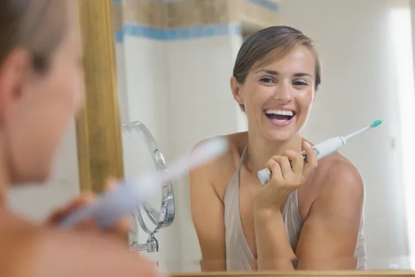 Feliz joven mujer disfrutando de los dientes limpios después de cepillarse la t eléctrica —  Fotos de Stock