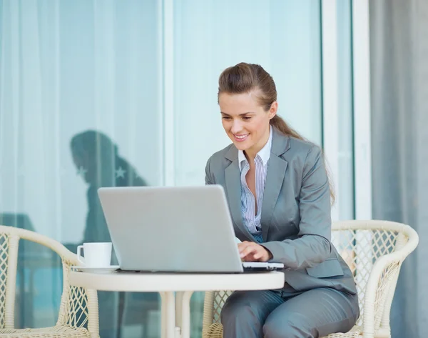 Heureuse femme d'affaires travaillant avec un ordinateur portable sur la terrasse — Photo