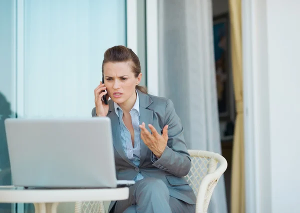 Concerned business woman talking cell phone on terrace — Stock Photo, Image
