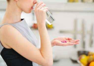 Closeup on young housewife eating pills and drinking water clipart