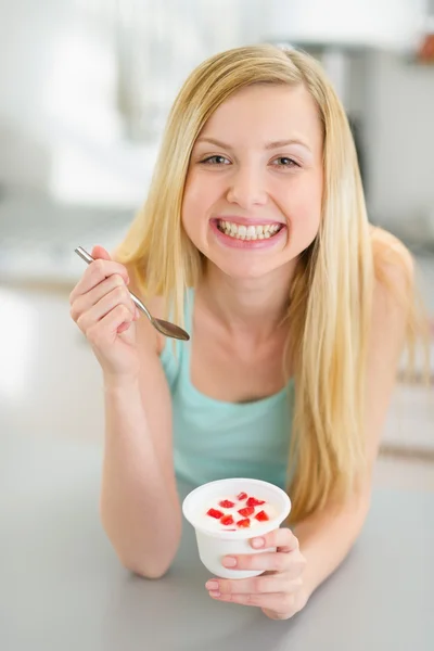 Uśmiechnięta dziewczyna nastolatka jedzenie jogurt w nowoczesnej kuchni — Zdjęcie stockowe