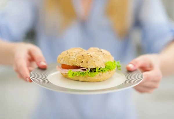 Närbild på tallrik med smörgås i handen av ung kvinna — Stockfoto