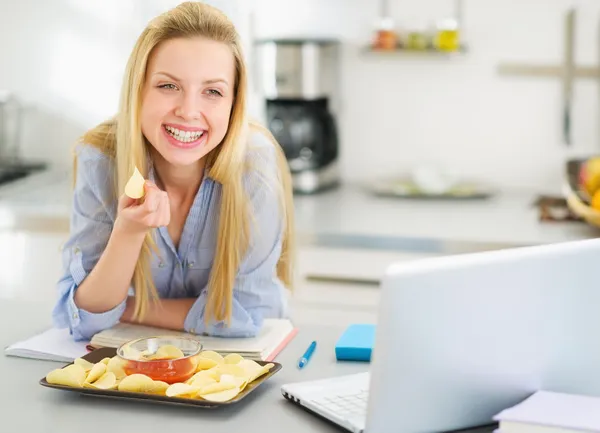 Adolescente ragazza mangiare patatine mentre si studia in cucina — Foto Stock