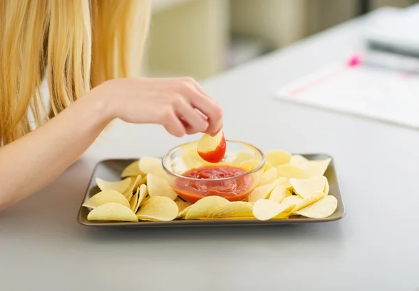 Крупный план девочки-подростка, макающей чипсы в соус — стоковое фото