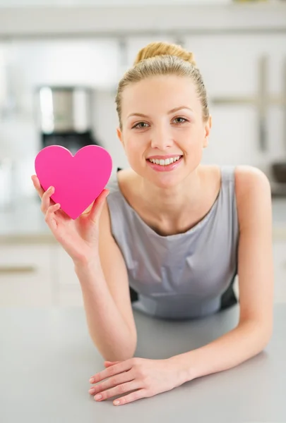 Glad ung kvinna visar dekorativt hjärta i köket — Stockfoto