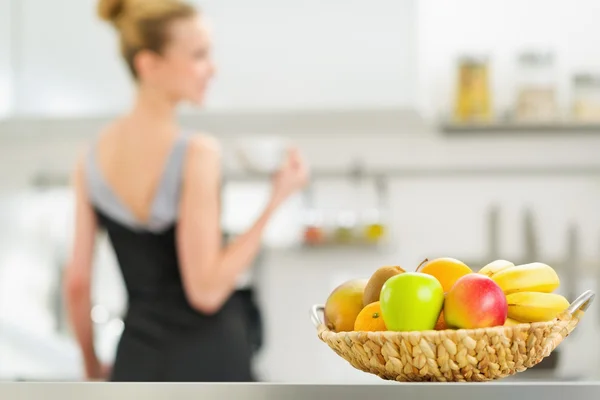 Крупный план на тарелке фруктов и молодая домохозяйка на заднем плане — стоковое фото