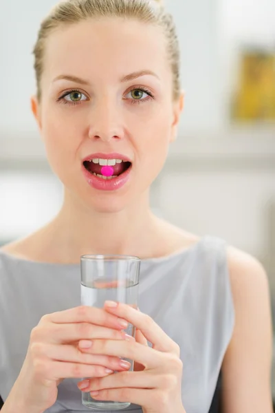 Jonge vrouw met pil in de mond — Stockfoto