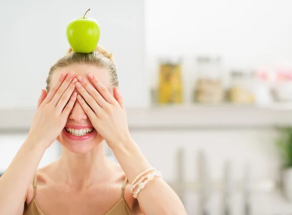 Happy teenage girl with apple on head closing eyes with hands — Stock Photo, Image