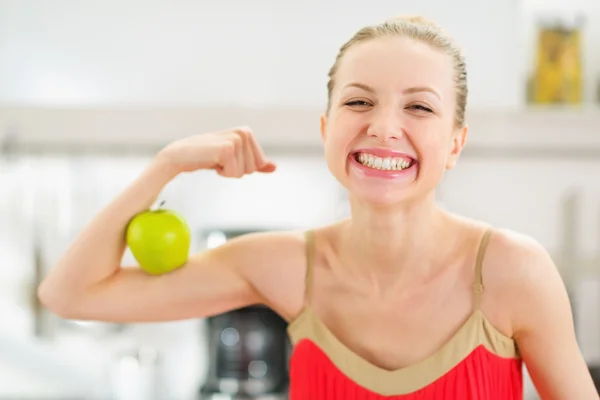 Happy teenage girl showing biceps and apple — Stock Photo, Image