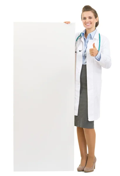 Porträtt av glad doktor kvinna visar tom billboard — Stockfoto