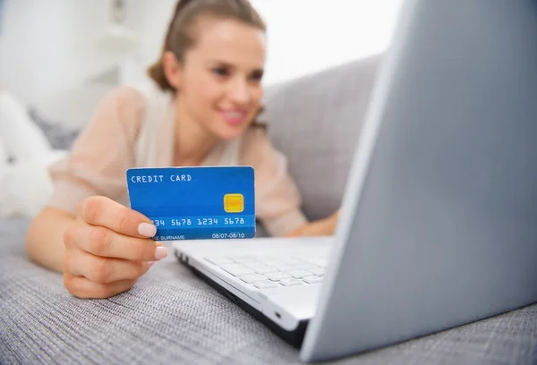 Closeup on credit card in hand of young woman laying on couch — Stock Photo, Image