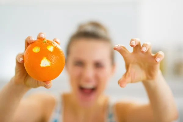 Primer plano en naranja con la cara santificante en la mano de la mujer joven — Foto de Stock