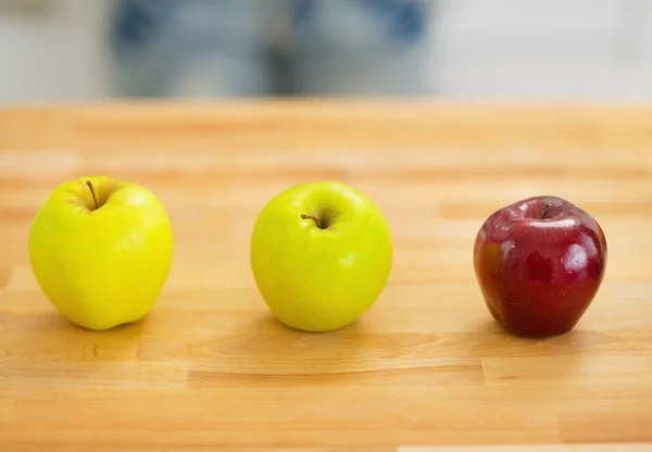 Two green and one red apple on cutting board — Stock Photo, Image