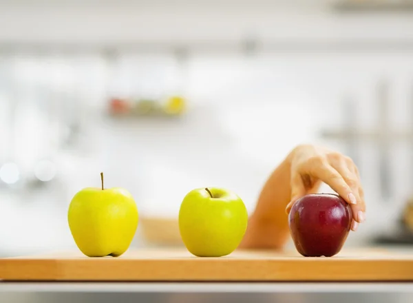 Closeup on hand choosing between two green and one red apple — Stock Photo, Image