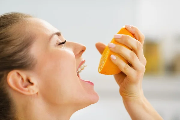 Young woman pressing orange juice in mouth — Stock Photo, Image