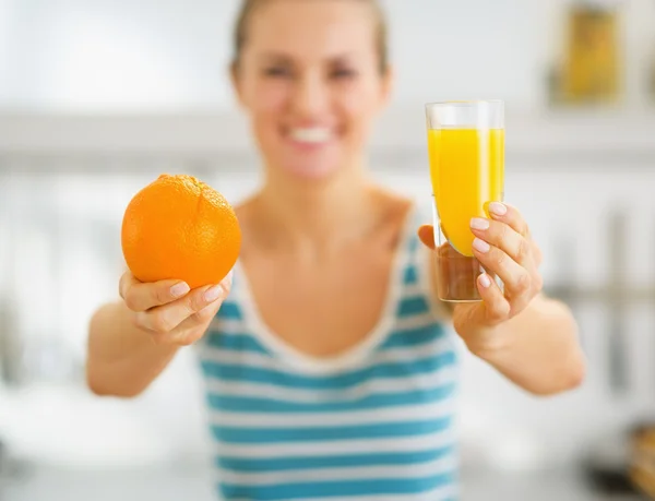 Glass of orange juice and orange in hand of young woman — Stock Photo, Image