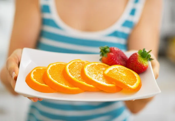 Primer plano en plato con fresa y naranja en mano de mujer —  Fotos de Stock