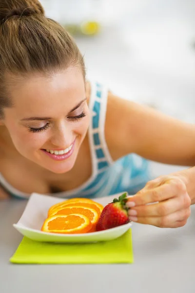 Happy young woman decorating plate with fruits — Stock Photo, Image