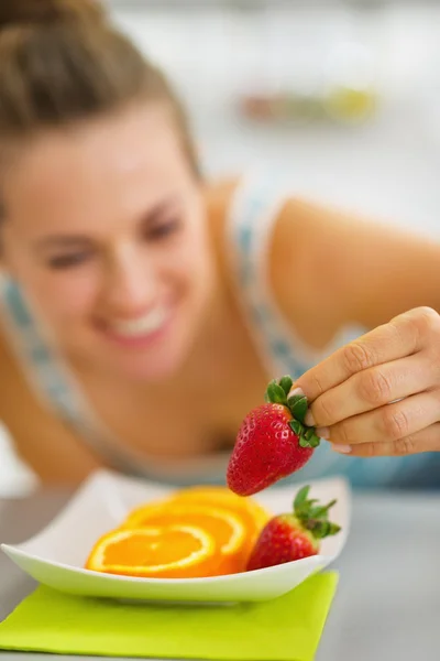 Closeup on happy young woman decorating plate with fruits — Stock Photo, Image