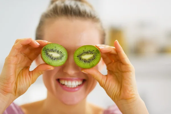 Happy young woman making eyes with kiwi slices — Stock Photo, Image