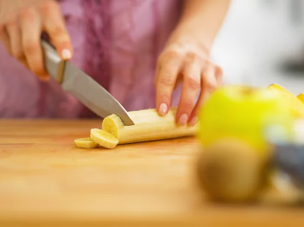 Primo piano sulla donna taglio banana sul tagliere — Foto Stock
