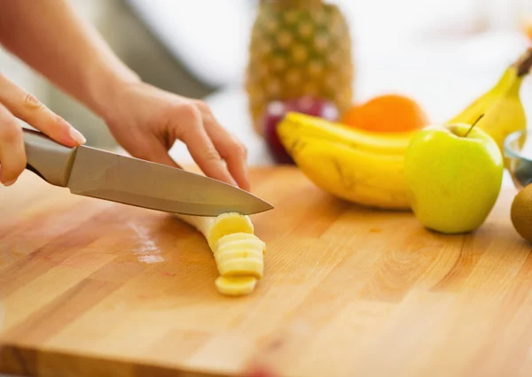 Close-up na mulher cortando banana na placa de corte — Fotografia de Stock