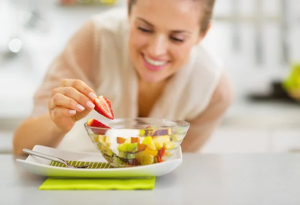 Happy young housewife decorating fruits salad — Stock Photo, Image