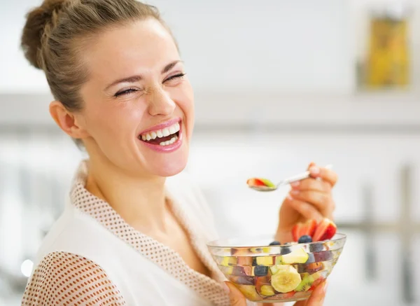 Sourire jeune femme au foyer manger de la salade de fruits — Photo