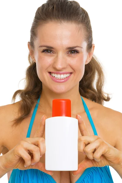 Portrait of smiling young woman in swimsuit showing bottle — Stock Photo, Image