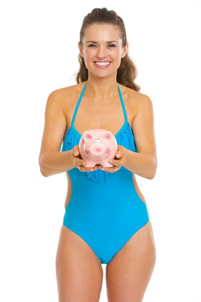 Glückliche junge Frau im Badeanzug gibt Sparschwein — Stockfoto