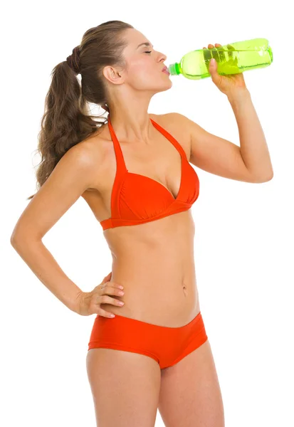 Jonge vrouw in zwembroek drinkend uit de fles water — Stockfoto