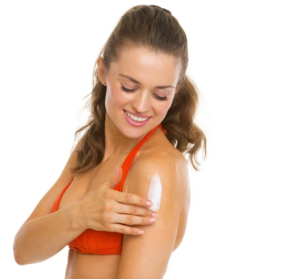 Mujer joven feliz en traje de baño aplicando crema protector solar —  Fotos de Stock