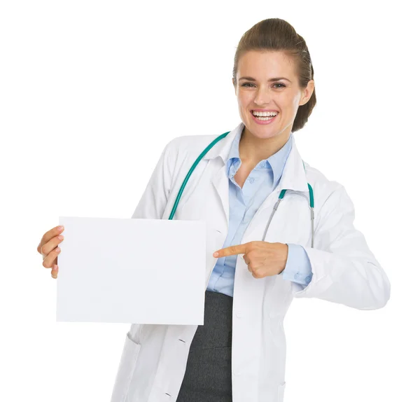 Uśmiechnięta kobieta lekarz, wskazując na arkuszu papieru puste — Zdjęcie stockowe