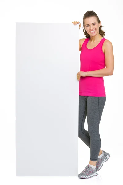 Souriant fitness jeune femme montrant panneau d'affichage vierge — Photo