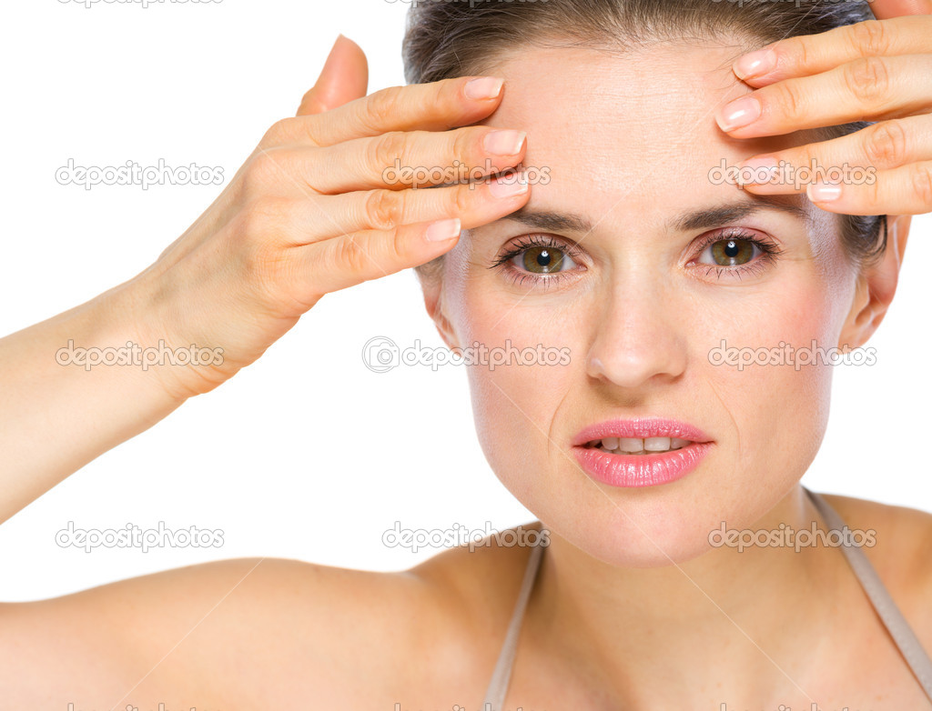Beauty portrait of concerned young woman checking facial skin