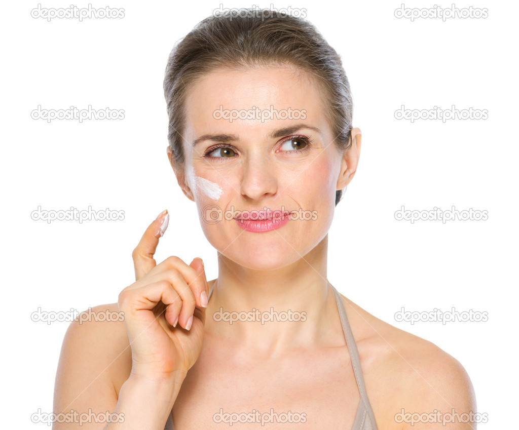 Beauty portrait of thoughtful young woman with creme on cheek