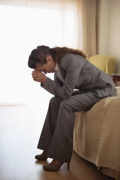 Besorgte Geschäftsfrau sitzt auf Bett im Hotelzimmer — Stockfoto