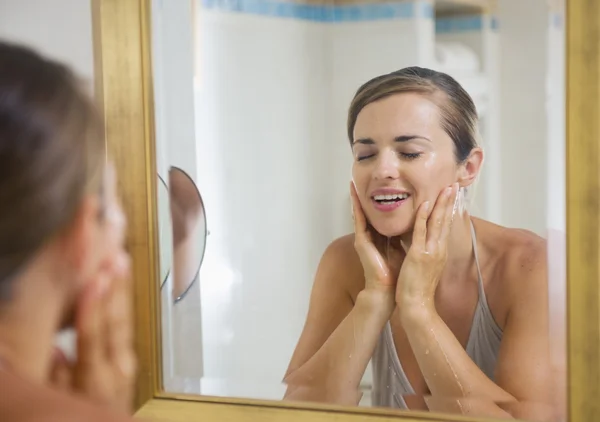 Glückliche junge Frau wäscht Gesicht im Badezimmer — Stockfoto