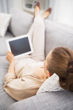 tablet pc ile kanepede döşenmesi genç bir kadın. arka görünüm