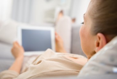 genç bir kadın divan tablet pc ile döşeme. arka görünüm