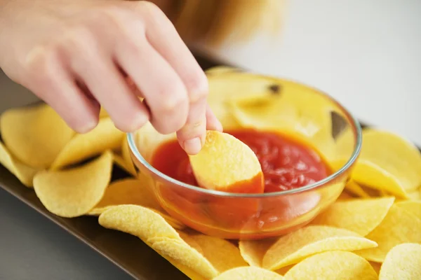 Крупным планом девушка кладет чипсы в соус — стоковое фото