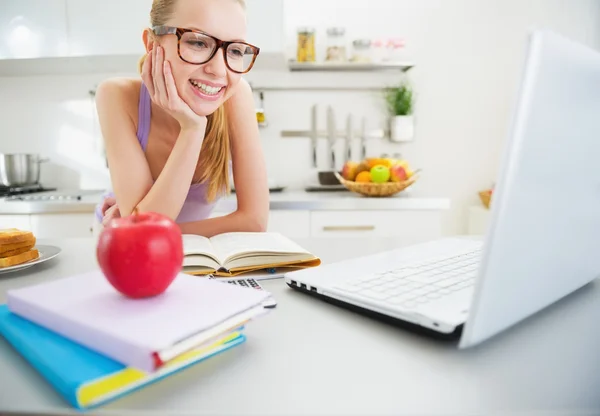 Sorrindo jovem mulher estudando na cozinha — Fotografia de Stock