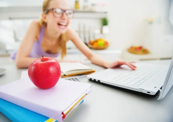 Närbild på apple och leende ung kvinna som studerar i kök i — Stockfoto