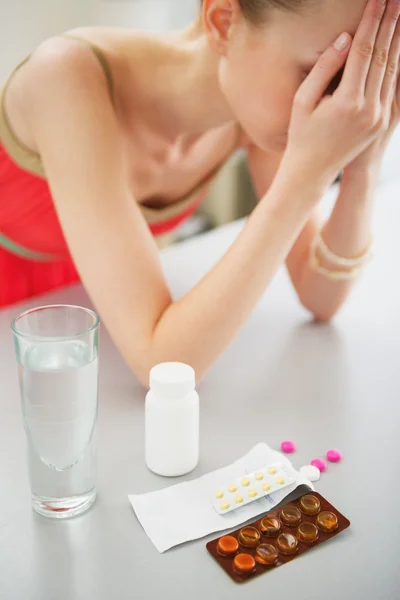 Close-up op de pillen op tafel en gevoel slecht meisje op achtergrond — Stockfoto