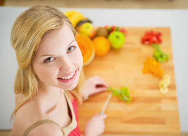 Porträtt av leende ung kvinna att göra fruktsallad — Stockfoto