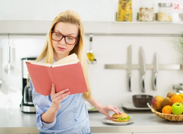 Ragazza adolescente che ha sandwich in cucina mentre studia — Foto Stock